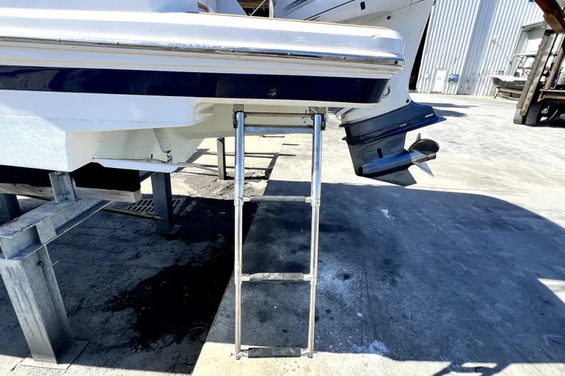 Slide: The Image of 2021 Regal 26 XO boat with extended ladder and outboard motor in a marina. - 8