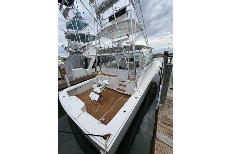 Slide: The Image of 2004 Cabo 40 Hardtop Express yacht docked, featuring spacious deck and fishing chair. - 3