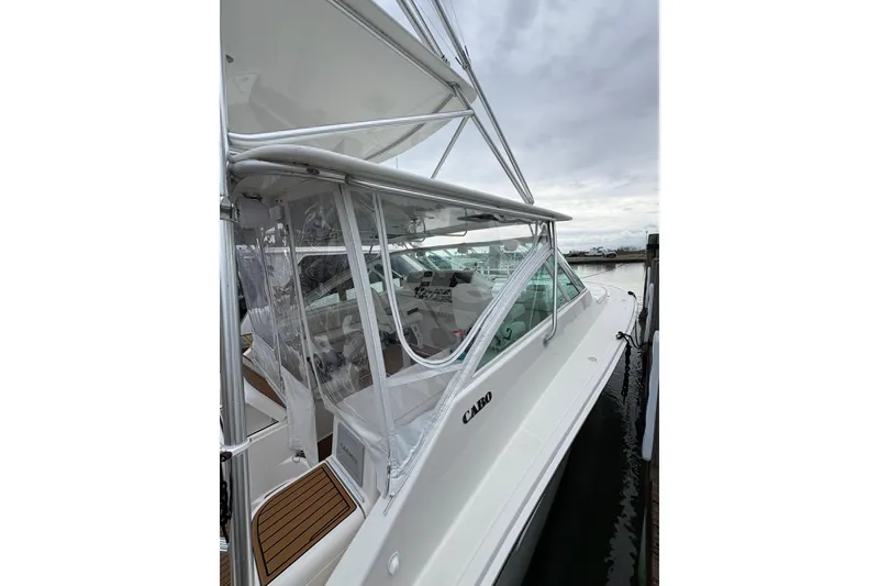 Slide: The Image of 2004 Cabo 40 Hardtop Express boat docked, featuring sleek design and clear enclosure. - 9