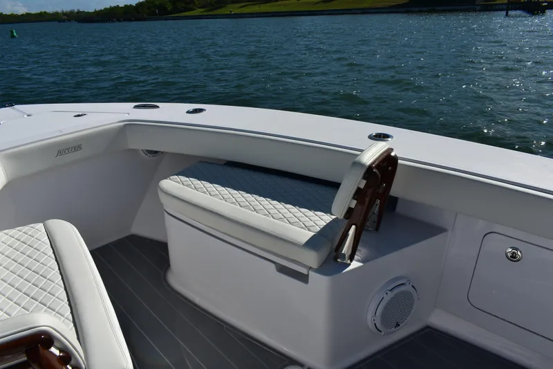 Slide: The Image of 2025 Jupiter 32 FS boat interior with cushioned seating, on a calm water backdrop. - 12