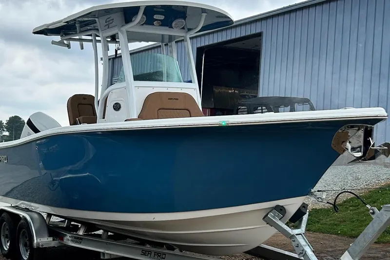 Slide: The Image of 2023 Sea Pro 239 Deep V CC boat on trailer, blue hull, parked near a building. - 2
