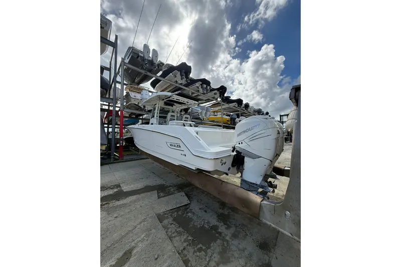 Slide: The Image of 2016 Boston Whaler 330 Outrage boat on a rack under a cloudy sky. - 3