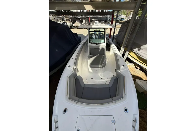 Slide: The Image of 2016 Boston Whaler 330 Outrage boat, docked under a shelter, showcasing spacious deck. - 8