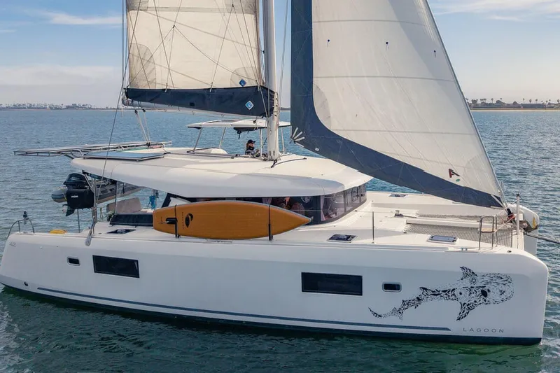 The Image of 2019 Lagoon 42 catamaran sailing on calm waters with a surfboard on deck. - 0