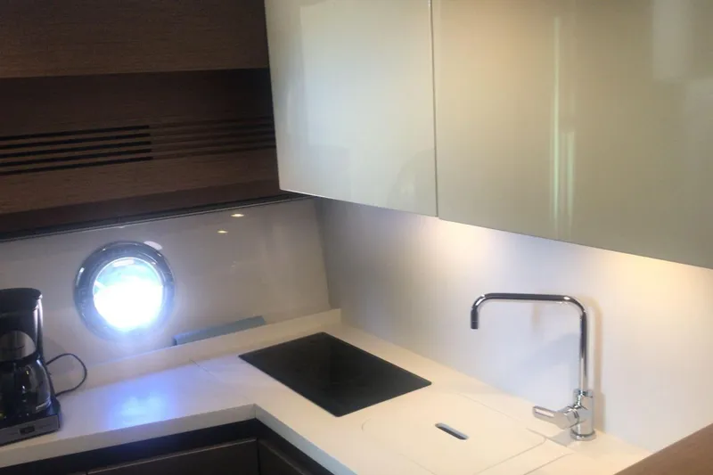 Slide: The Image of Modern kitchen interior on 2020 Beneteau Gran Turismo 46 yacht, featuring sleek cabinetry and porthole window. - 20