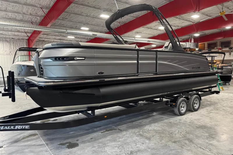 The Image of 2026 Sylvan L-5 Platinum pontoon boat in a showroom on a trailer. - 1