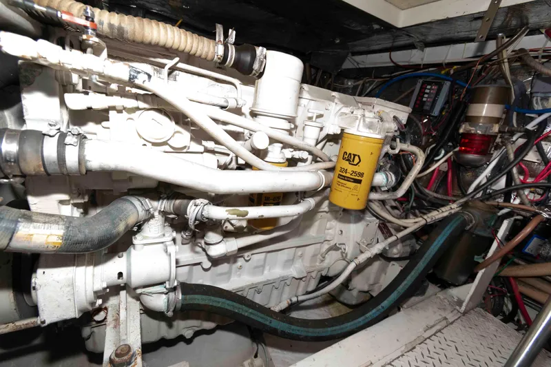 Slide: The Image of Engine room of 1996 Trojan 440 Express Yacht with visible CAT filter and hoses. - 24