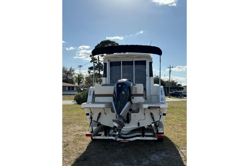 Slide: The Image of 2026 Trophy T 25 Explorer boat with outboard motor, parked on grass under clear sky. - 18