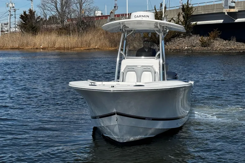 Slide: The Image of 2019 Regulator 25 boat interior with cushioned seating and cup holders at a marina. - 56