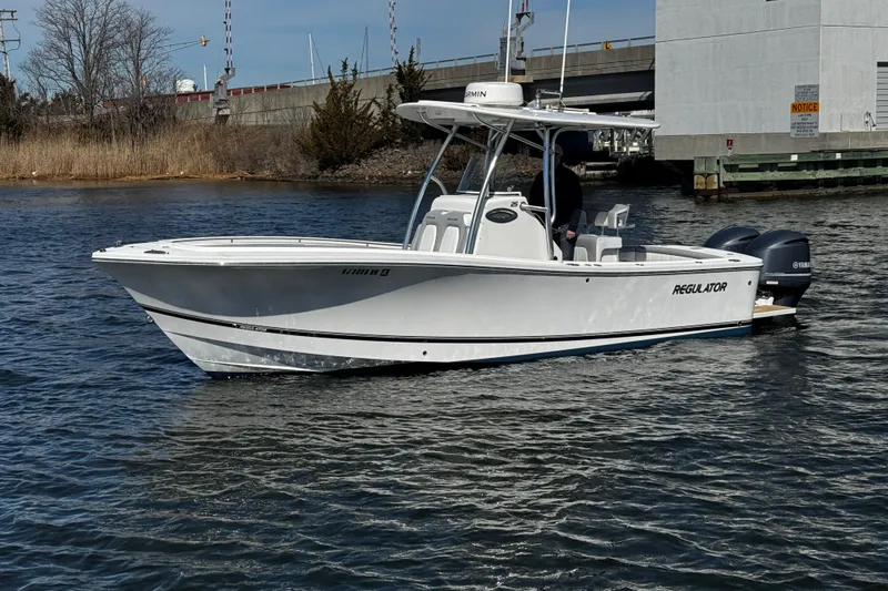 Slide: The Image of 2019 Regulator 25 boat interior with cushioned seating and cup holders at a marina. - 57