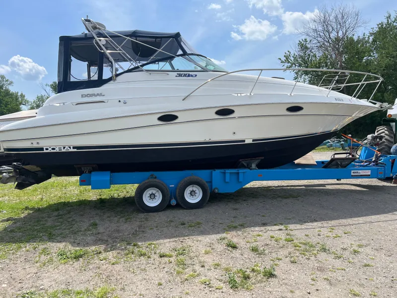 The Image of 1999 Doral 300 SC boat on blue trailer outdoors. - 0
