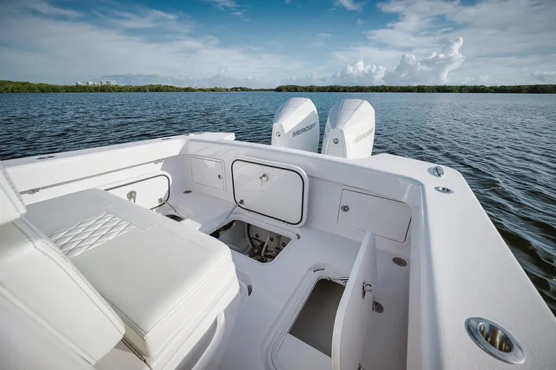 Slide: The Image of 2024 Birdsall 30 boat interior with storage compartments and twin engines on a calm lake. - 25