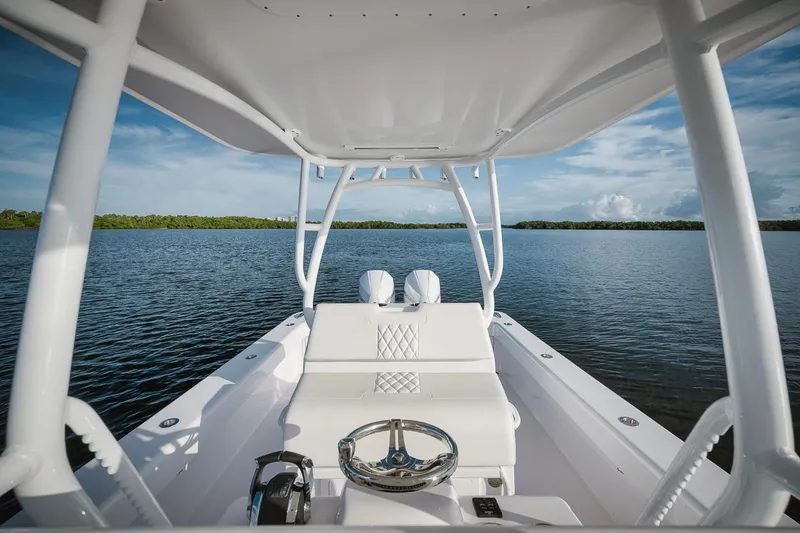 Slide: The Image of 2024 Birdsall 30 boat interior with steering wheel and seating, on a calm lake. - 6