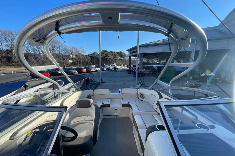 Slide: The Image of 2014 Yamaha Boats 242 Limited S interior with seating and helm, parked outdoors. - 13
