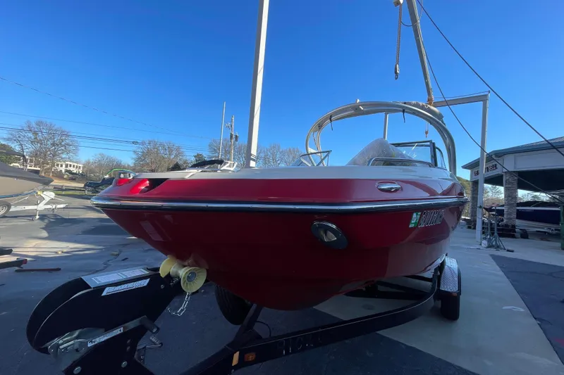 Slide: The Image of 2014 Yamaha Boats 242 Limited S, red hull, parked on trailer, clear blue sky. - 5