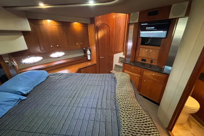 Slide: The Image of Luxurious 2005 Cruisers Yachts 455 Express Motoryacht bedroom with wood cabinetry and modern amenities. - 24