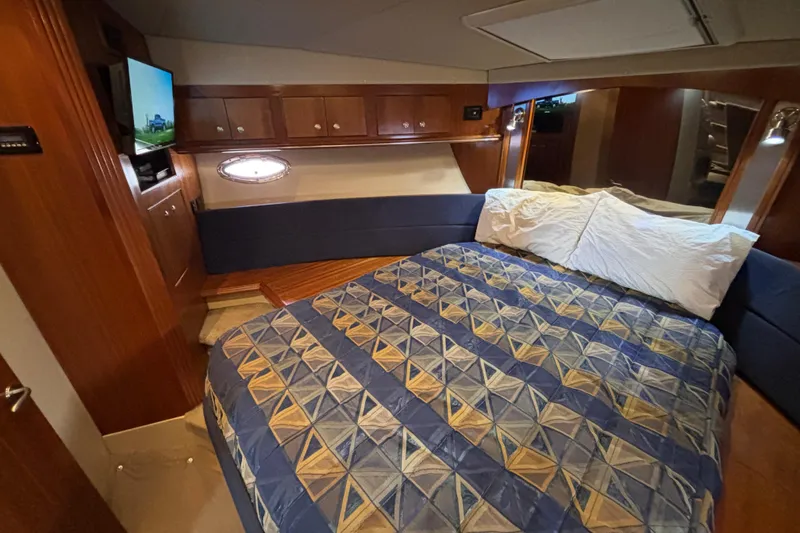 Slide: The Image of Luxurious forward stateroom in 2005 Cruisers Yachts 455 Express Motoryacht with cozy bedding and wood accents. - 16
