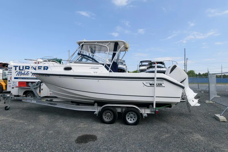 The Image of 2001 Boston Whaler 23 Conquest boat on trailer, parked outdoors under clear sky. - 1