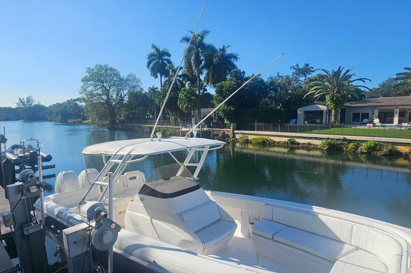 Slide: The Image of 2015 Intrepid 327 Center Console boat docked by a scenic waterfront with palm trees. - 10