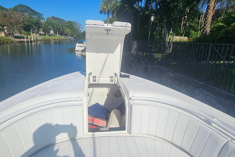 Slide: The Image of 2015 Intrepid 327 Center Console boat with open storage compartment on a sunny day. - 12