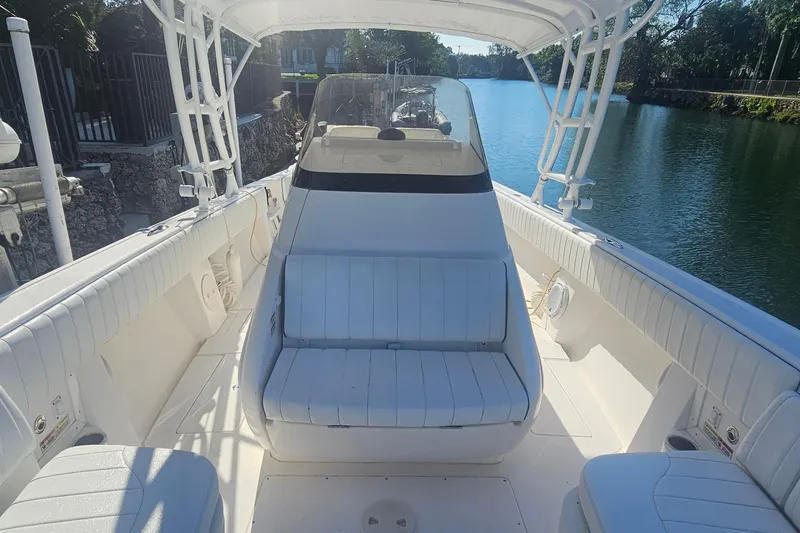 Slide: The Image of 2015 Intrepid 327 Center Console boat interior with seating, docked by a serene waterway. - 14