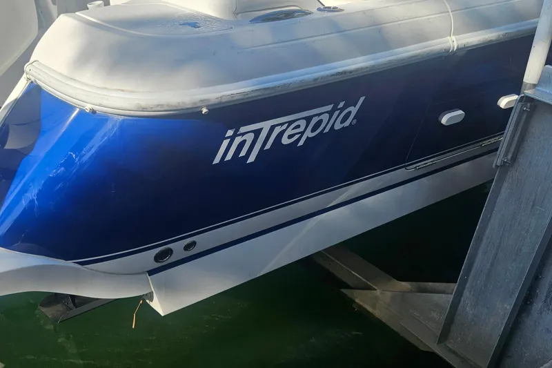 Slide: The Image of 2015 Intrepid 327 Center Console boat docked, featuring a sleek blue and white design. - 3