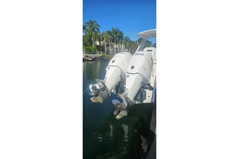 Slide: The Image of Twin outboard engines on a 2015 Intrepid 327 Center Console boat, docked by palm trees. - 4