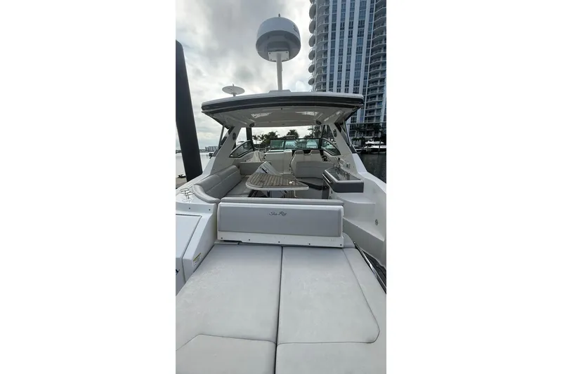 Slide: The Image of 2021 Sea Ray Sundancer 320 yacht with spacious deck and modern amenities, docked near high-rise buildings. - 8