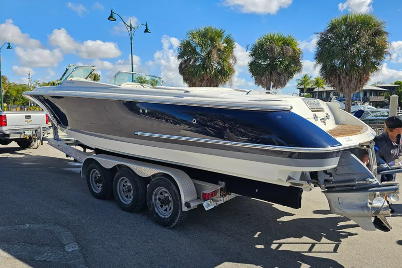 Slide: The Image of 2008 Chris-Craft Launch 28 boat on trailer, parked near palm trees under blue sky. - 3