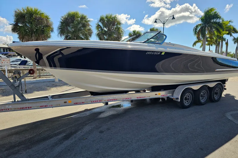 Slide: The Image of 2008 Chris-Craft Launch 28 boat on trailer, parked near palm trees under a sunny sky. - 4