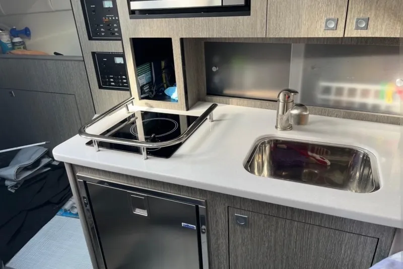Slide: The Image of Compact kitchen area in 2021 Monterey 295 Sport Yacht with stove, sink, and fridge. - 10
