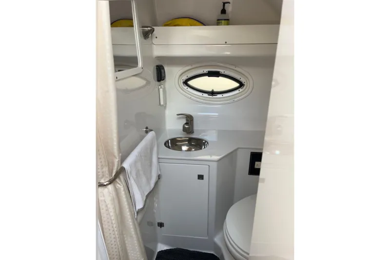 Slide: The Image of 2021 Monterey 295 Sport Yacht bathroom with sink, mirror, and porthole window. - 14