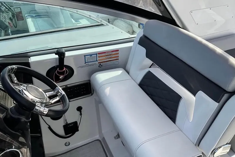 Slide: The Image of 2021 Monterey 295 Sport Yacht helm with sleek steering wheel and cushioned seating. - 5