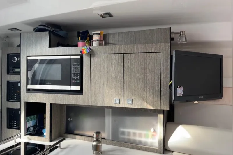 Slide: The Image of 2021 Monterey 295 Sport Yacht interior kitchen with microwave and TV. - 9