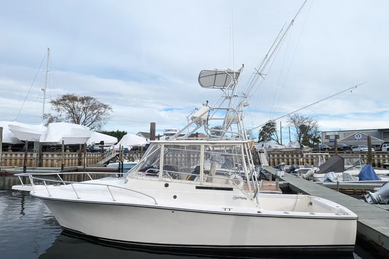 The Image of 1996 Henriques 28 Express boat docked at marina under cloudy sky. - 1