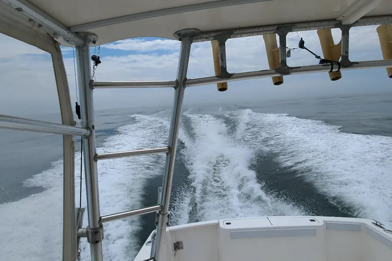 Slide: The Image of 1996 Henriques 28 Express boat cruising on open water, leaving a wake behind. - 28