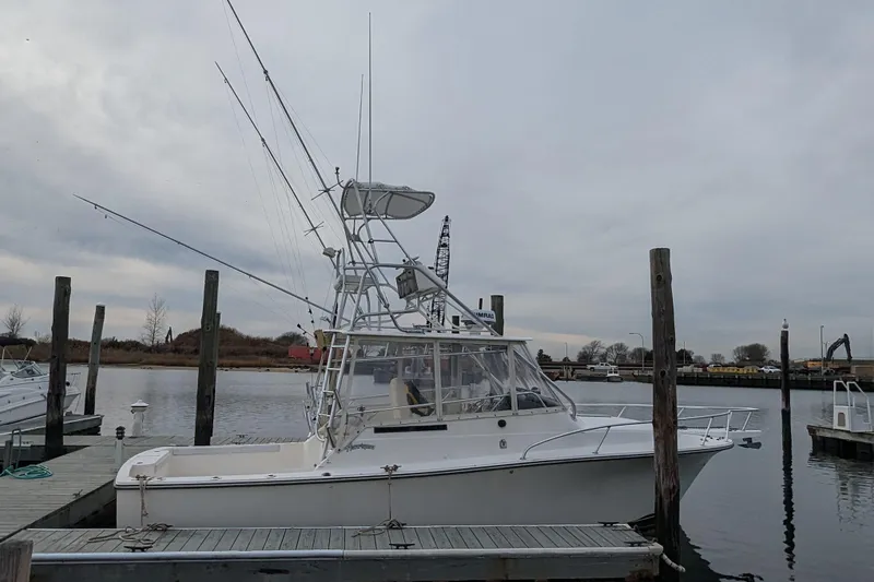 Slide: The Image of 1996 Henriques 28 Express boat docked at marina under cloudy sky. - 31