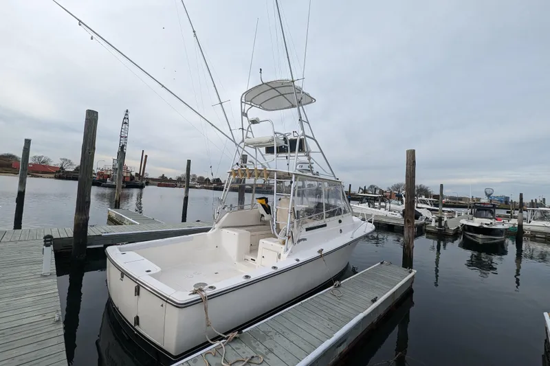 Slide: The Image of 1996 Henriques 28 Express boat docked at marina, featuring fishing tower and spacious deck. - 4