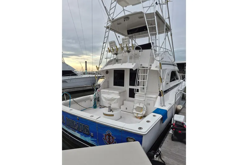 Slide: The Image of 1995 Bertram 43 Convertible yacht docked, featuring a spacious deck and fishing equipment. - 2