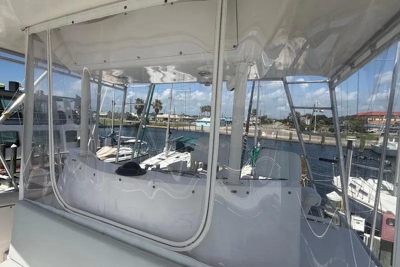 Slide: The Image of 1995 Bertram 43 Convertible yacht interior with marina view, featuring clear enclosures and helm station. - 11