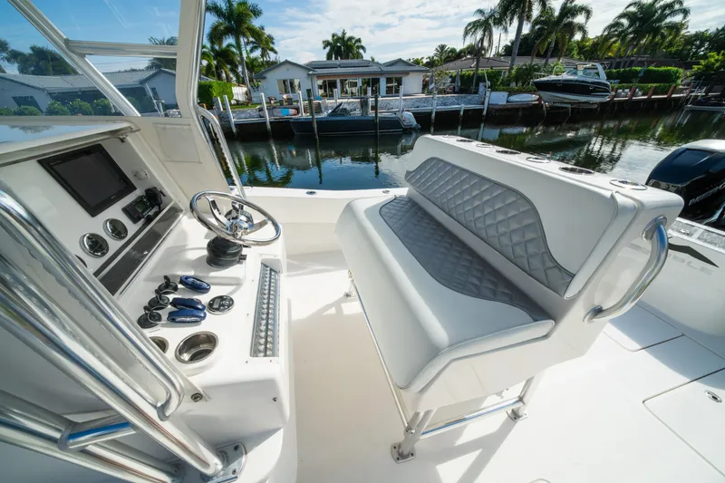 Slide: The Image of 2016 Invincible 36 Open Fisherman boat interior with steering console and seating, docked by waterfront homes. - 4