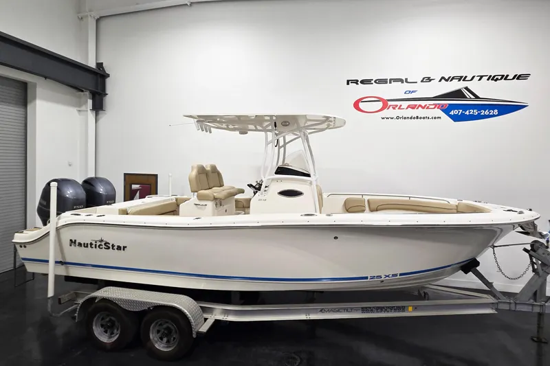The Image of 2018 NauticStar 25 XS boat on trailer in showroom setting. - 0