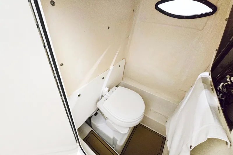 Slide: The Image of Compact marine toilet in 2018 NauticStar 25 XS boat cabin, featuring a small window. - 19