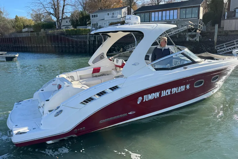 The Image of 2012 Chaparral 327 SSX boat named "Jumpin' Jack Splash" on the water near houses. - 0