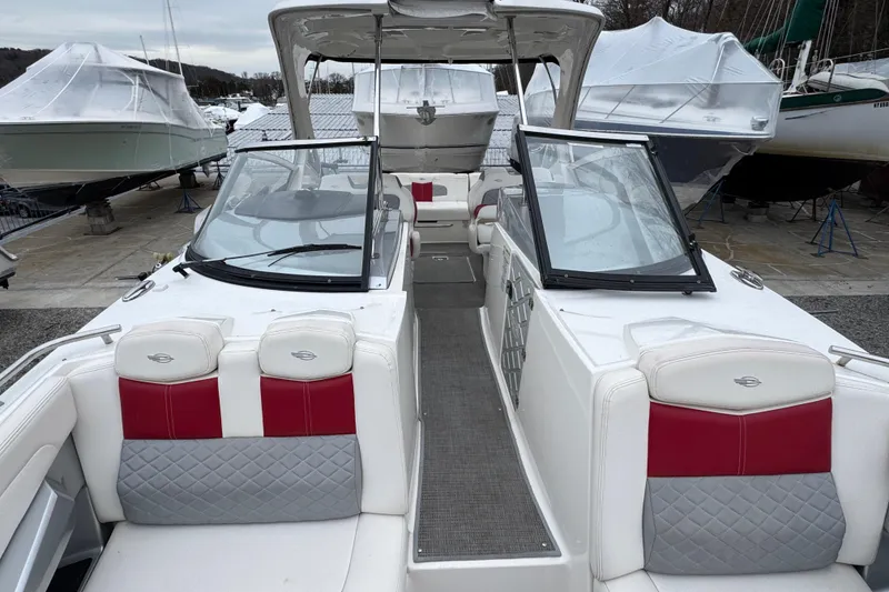Slide: The Image of 2012 Chaparral 327 SSX boat with white and red interior, docked among covered boats. - 13
