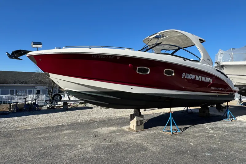 Slide: The Image of 2012 Chaparral 327 SSX boat on stands, red and white hull, clear blue sky. - 4