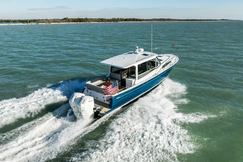Slide: The Image of 2026 MJM 47R boat cruising on open water, displaying American flag. - 47