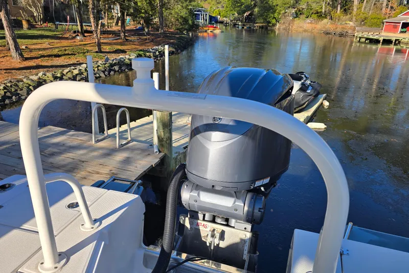 Slide: The Image of 2022 Robalo 246 Cayman SD boat docked by a serene lakeside. - 7