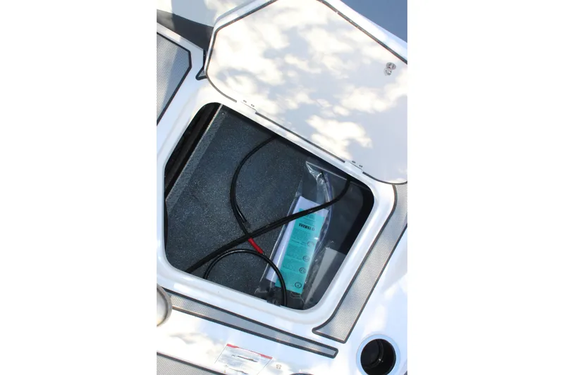 Slide: The Image of Open storage compartment in 2026 Starcraft SV 18 OB boat, showing cables and manual. - 10