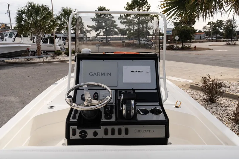 Slide: The Image of 2021 ShearWater 25LTD boat dashboard with Garmin and Mercury controls, parked outdoors. - 13